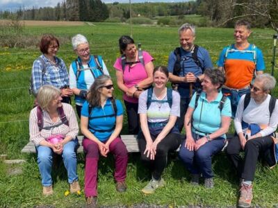 Das Foto zeigt die Teilnehmer der Wandergruppe auf einer Bank sitzend und dahinter stehend.