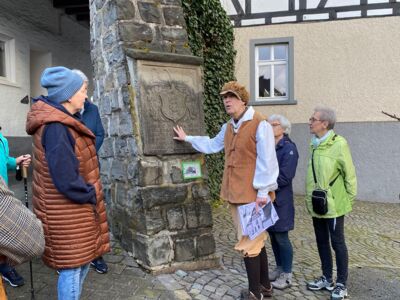 Der Stadtführer gibt den Teilnehmern an einer historischen Steintafel Erläuterungen.
