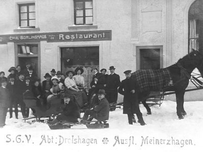 Das Foto zeigt ein Pferd mit Pferdeschlitten im Schnee. Auf dem Schlitten sitzen mehrere Personen. Weitere Personen gruppieren sich um den Schlitten.