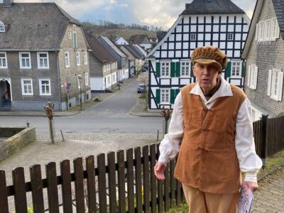 Der Stadtführer steht auf dem Weg oberhalb des Hotels "Zur alten Quelle". Im Hintergrund ist die Brückstraße zu sehen.