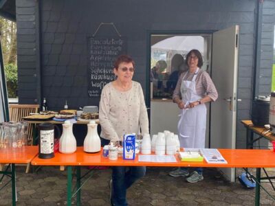 Auf dem Foto sind zwei Frauen vom Helferteam zu sehen, die an der Ausgabe von Kaffee und Kuchen stehen.