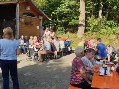 Bild mit an Tischen sitzenden und an Stehtischen stehenden Gästen.