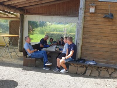 Mehrere Personen in geselliger Runde sitzend an einem Tisch an der SGV-Hütte. - Foto SGV Drolshagen
