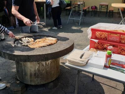 Betreuer am Grill. Es gibt Würstchen im Brötchen.