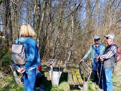 Die Wandergruppe steht bzw. sitzt an einer Sitzgruppe oberhalb der Ortschaft Wormberg.