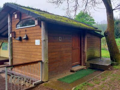 Auf dem Foto ist das separat stehende Toilettengebäude mit einem überdachten Sitzbereich zu sehen.