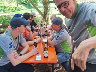 Gruppenbild mit Männern an einem Tisch sitzend.
