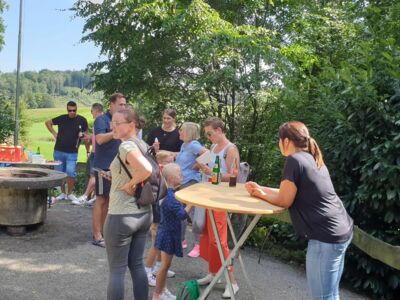 Mehrere Kinder und Erwachsene in geselliger Rund an der SGV-Hütte