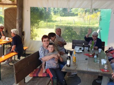 Besucher sitzen an Tischen bei Kaffee und Kuchen sowie Kaltgetränken.