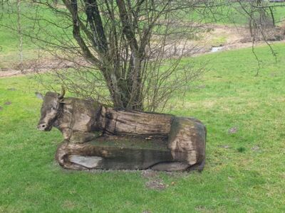 Die Holzskulptur eines Rindviehs mit integrierter Sitzbank.